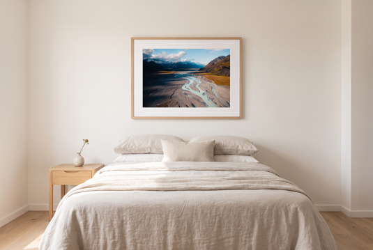 New Zealand glacial rivers print framed above a bed in a minimalist bedroom